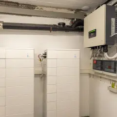 Dwa białe, modułowe systemy **bess** obok siebie, podłączone do falownika i rozdzielnicy elektrycznej.
