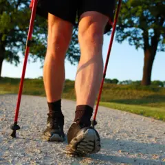 Nogi w butach i skarpetach, z kijkami nordic walking. Dowiedz się, jak prawidłowo założyć buciki na kijki nordic walking, by cieszyć się spacerem.