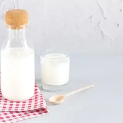 Bouteille de lait et verre sur une serviette à carreaux. Le lait battu, c'est quoi ? C'est ce lait frais et crémeux.