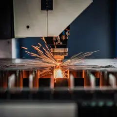 Precyzyjna obsługa maszyn CNC: laser tnie metal, sypią się iskry.