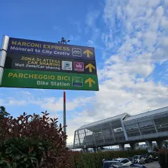 Znak na lotnisku w Bolonii wskazuje drogę do Marconi Express, strefy car-sharing i parkingu rowerowego.