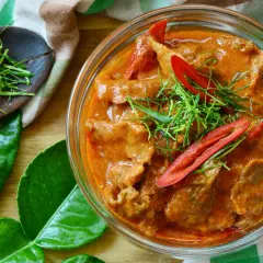 Un délicieux boeuf curry rouge, garni de piments et d'herbes fraîches, prêt à être dégusté.