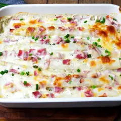 Ein köstlicher Kartoffel Spargel Auflauf mit Schinken und Käse überbacken, garniert mit frischen Kräutern.