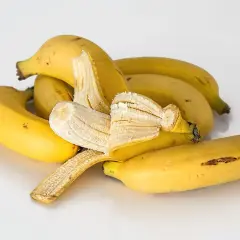 Kupa żółtych bananów, jeden częściowo obrany. Czy banan jest lekkostrawny? Tak, to świetna przekąska.