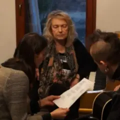 Katarzyna Gaertner z synem i młodą kobietą analizują nuty przy pianinie.