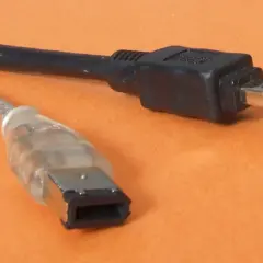 Dwa kable: jeden przezroczysty z szeroką wtyczką, drugi czarny z małą wtyczką. To złącza FireWire IEEE 1394.