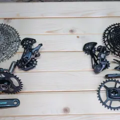 Porównanie grup osprzętu rowerowego: SRAM vs Shimano. Widoczne kasety, przerzutki, korby i manetki.