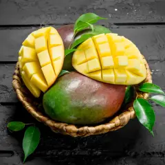Koszyk z dojrzałymi mango, jedno przekrojone w kostkę. Czy zastanawiałeś się nad mango indeks glikemiczny?