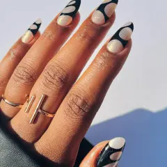 Unghie lunghe e affusolate con decorazione a pois bianchi e neri, realizzate con acrygel. Brillanti e alla moda.