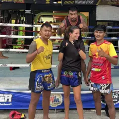Fyra personer poserar i en ring för c4 thaiboxning. En kvinna i mitten med tränare på var sin sida.
