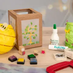 Bastelmaterialien für eine St. Martin Laterne: Bienen-Laterne, Baum-Laterne, Kleber, Stempel und Schmetterlingsstanzer.