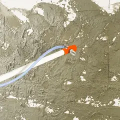 Obrzutka cementowa na ścianie, nakładana za pomocą narzędzia z wężem.
