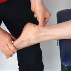 Mains appliquant un massage sur le tendon d'Achille d'une cheville.