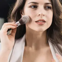 Donna applica il primer con un pennello, creando una base perfetta per il trucco.