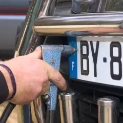 Mano con rivettatrice che fissa una targa auto, forse per cambiare targa auto per sfizio.