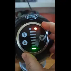 Dłoń naciska przycisk na ekspresie Dolce Gusto. Czerwona lampka sygnalizuje problem, a zielona wskazuje, że dolce gusto cieknie woda.