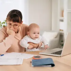 Mère pensive avec bébé, jonglant entre le travail et le renouvellement congé parental CAF.