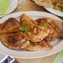 En tallrik med gyllene, friterade samosas, perfekt för ett samosa recept. Garnerade med färsk koriander.