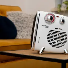Kompaktowy grzejnik Vulcan, idealny do dogrzewania garażu, stoi na stoliku obok kanapy.
