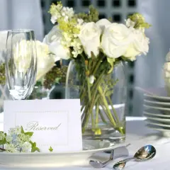 Elegancko nakryty stół z białymi różami, kieliszkami i kartą "Reserved". Idealny na przyjęcie, gdzie wedding planner cena jest kluczowa.