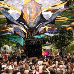 Bunte Stoffbahnen überspannen die Menge auf dem Wunderland Festival. Seifenblasen steigen auf, während die Besucher tanzen.