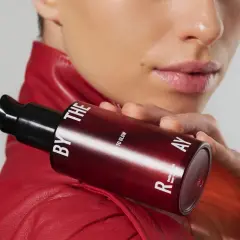 Kobieta w czerwonej ramonesce trzyma buteleczkę z serum. Czy to kwasy PHA jakie to? Delikatne dla skóry, dla blasku.