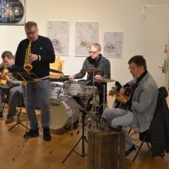 Jazzband spelar i galleri med konst av Kerstin Bengtsson Norén. Saxofonist, gitarrist och trummis.