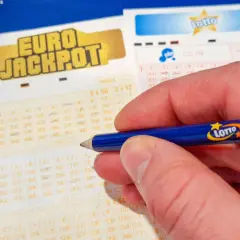 Dłoń z ołówkiem Lotto na kuponie Eurojackpot. Zastanawiasz się, dlaczego los w Eurojackpot w Polsce jest droższy?