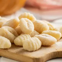 Gnocchis faits maison sur une planche en bois. La question "quelle pomme de terre pour gnocchi" est résolue avec ces petites bouchées parfaites.
