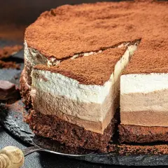 Tarta tres chocolates, con capas de mousse de chocolate blanco, con leche y negro, espolvoreada con cacao.
