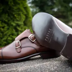 Eleganckie brązowe buty z podwójnymi klamrami, wykonane z wysokiej jakości kruponu. Widoczna podeszwa z logo marki.