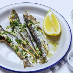 Tres sardinas a la plancha, doradas y jugosas, con perejil y ajo picado, acompañadas de limón y sal.