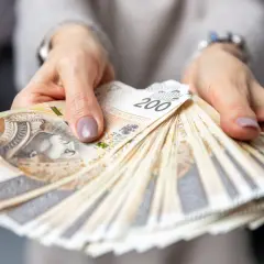 Dłonie trzymające plik banknotów 200 zł. Czy to wynagrodzenie pracownika hotelu?