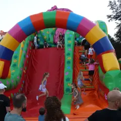 Radosny dzień dziecka w Krakowie! Dzieci wspinają się i zjeżdżają z kolorowej, dmuchanej zjeżdżalni w kształcie tęczy i dżungli.