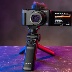 Nowoczesne bezlusterkowce Sony na statywie z mikrofonem. Ekran pokazuje menu sieciowe, idealne do vlogowania.