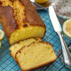 Un delicioso pastel de limón recién horneado, cortado en rebanadas y enfriándose en una rejilla, con rodajas de limón fresco al lado.