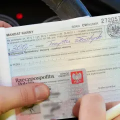 Ręce trzymają mandat karny na 300 zł. Wpisano "trzysta złotych", ale nie widać, ile punktów ma młody kierowca.