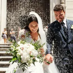 Novios felices salen de la iglesia, cubiertos de arroz. Parecen soñar con arroz, un día perfecto.