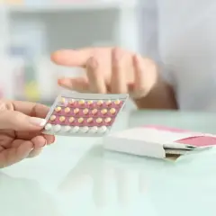 Dłoń trzyma blister tabletek antykoncepcyjnych. Farmaceuta wyjaśnia, bibloc na co.