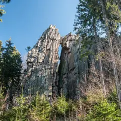 Skalny mostek na rudawych janowickich szczytach, otoczony drzewami.