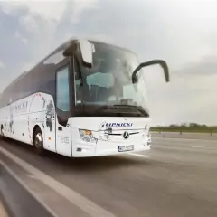 Biały autokar firmy Lipnicki jedzie po drodze, widok z przodu.