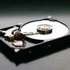 Odkryty dysk twardy, idealny jako dodatkowy dysk do laptopa. Widoczny talerz i głowica odczytująca.