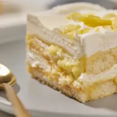 Ein Stück cremiges Lemon Tiramisu mit Löffel auf einem Teller.
