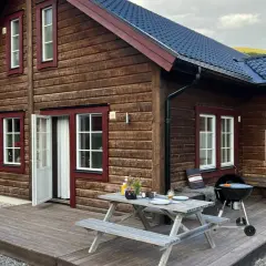 Mysig trästuga med grill och picknickbord på altanen, perfekt för en avkopplande vistelse på buskvallen inn.