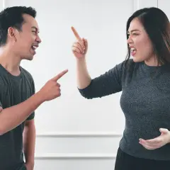 Pareja discutiendo, él señala acusadoramente, ella levanta el dedo en señal de enfado. Parece que están a punto de soñar que discuten con alguien.