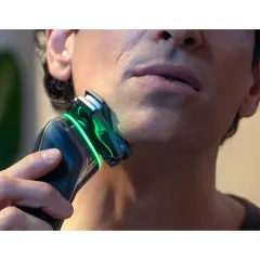 Mężczyzna goli twarz golarką Philips z zielonym podświetleniem.