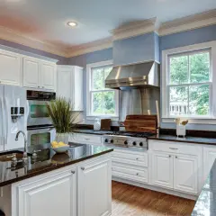 A bright kitchen with white cabinets and granite countertops. Learn how to care for granite to keep it looking its best.