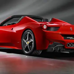 Czerwony kabriolet Ferrari 458 Spider z opuszczonym dachem, prezentujący swoje sportowe linie i potężne tylne światła.