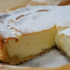 Une part de tarte à la ricotta sucrée, saupoudrée de sucre glace, révèle sa garniture crémeuse et sa croûte dorée. Un délice !