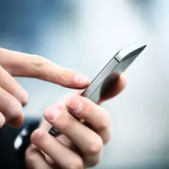 Dłoń z palcem wskazującym dotyka ekranu smartfona, który może służyć jako citi mobile token do bezpiecznych transakcji.